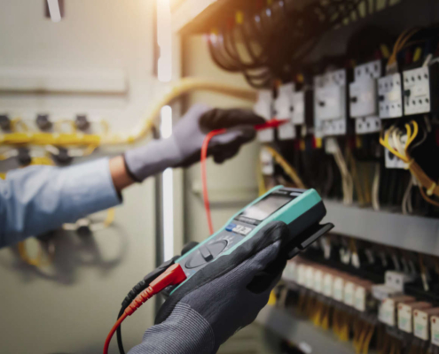 Electricity and electrical maintenance, engineer hand hold AC multimeter checking electrical voltage at circuit breaker terminal and cable wiring main power distribution.