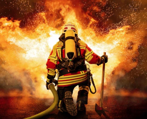 A firefighter kneels in front of the fire